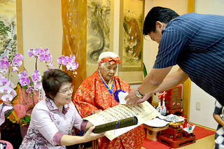 中山義隆市長から新１００歳の記念品を受け取る野崎千代さん＝21日午前、市内登野城の自宅