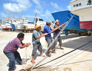 台風接近に備え、陸揚げした漁船をロープで固定した漁業者ら＝26日午前、登野城漁港