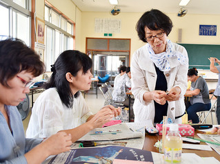 西村佑子氏（右）の指導で新聞紙を使ったコサージュ作りに挑戦する会員＝５日午後、新川公民館