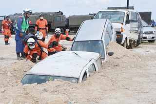 竹富町では初めて実施された県総合防災訓練。土砂に埋まった車両の負傷者の有無を確認する消防士ら＝３日午後、仲間港