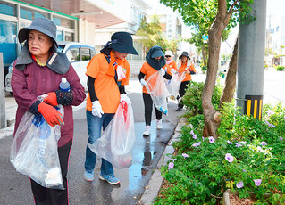 道路クリーン作戦で歩道の植樹帯を清掃する参加者＝25日午前、新栄町