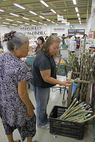 仏壇へ供えるサトウキビを品定めをする買い物客＝２日午前、ＪＡおきなわファーマーズマーケットやえやま「ゆらてぃく市場」