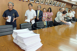 中山義隆市長に署名簿（手前）を提出した後、「市民の意思の尊重を」と訴える嶺井善共同代表（左）ら＝19日午後、庁議室
