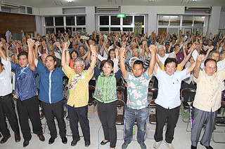 手を取り合って「頑張ろう」を三唱する支持者ら＝13日夜、大川公民館
