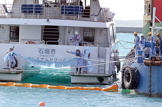 海面に流出した油を吸着シートで除去する訓練を行う参加者ら＝９日午後、石垣港