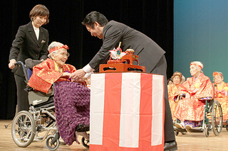 あやかりの杯の後、中山義隆市長から長寿を祝福される１０８歳の慶田城ヒテさん＝16日午後、市民会館大ホール