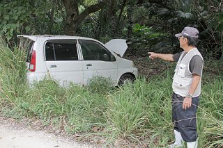 道路横の草むらに放置された軽自動車＝2018年12月23日、黒島
