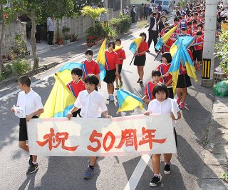 新川小学校創立50周年を記念し校区内をパレードする児童ら＝22日午前、石垣市新川
