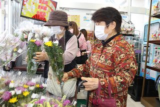 正月飾り用の生花などを品定めする買い物客ら＝29日午後、サンエー石垣シティ