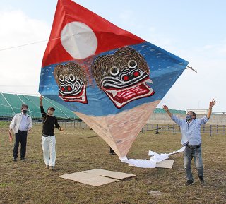 シーサーを描いた大型凧を揚げる多田浜会の会員ら＝9日午前、先島ガス私有地