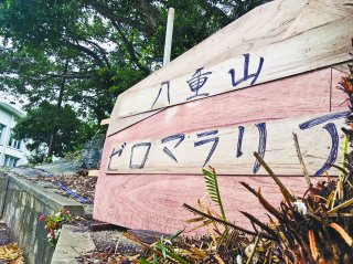 「ゼロマラリア達成の碑」建立予定の伊野田公民館入口。原寸大に近いサイズのベニア板が設置されている＝29日午後、伊野田