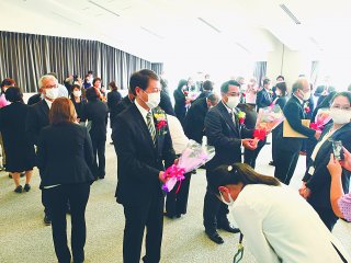 職員から花束を受ける定年退職者ら＝3月31日、石垣市役所