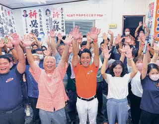 トップ当選を果たした髙良宗矩氏。「万歳」をして支持者と喜びを分かち合う＝11日夜、新川の事務所