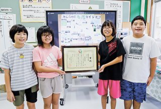 県知事賞を受賞した名蔵小学校5、6年生の児童ら。奥のスクリーンは製作したマップ＝12日午後、名蔵小学校