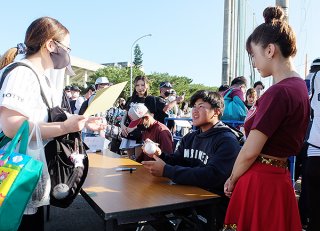 笑顔でサインする松川虎生捕手。ファンも「子どもが好きなんです」と大喜びだった＝12日夕、石垣市中央運動公園内