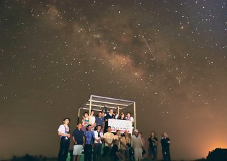 天の川をバックに記念撮影するツアー客ら＝7日夜、展望台
