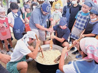 蒸したもち米にアワと小豆を混ぜ、練りこんで「イイヤチ」をつくる児童生徒ら＝16日午後、竹富島旧与那国家住宅