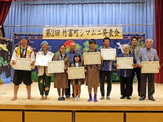 第2回竹富町シマムニ発表会に出場し、表彰を受けた4組8人の皆さん（前列）＝9日午後、小浜公民館